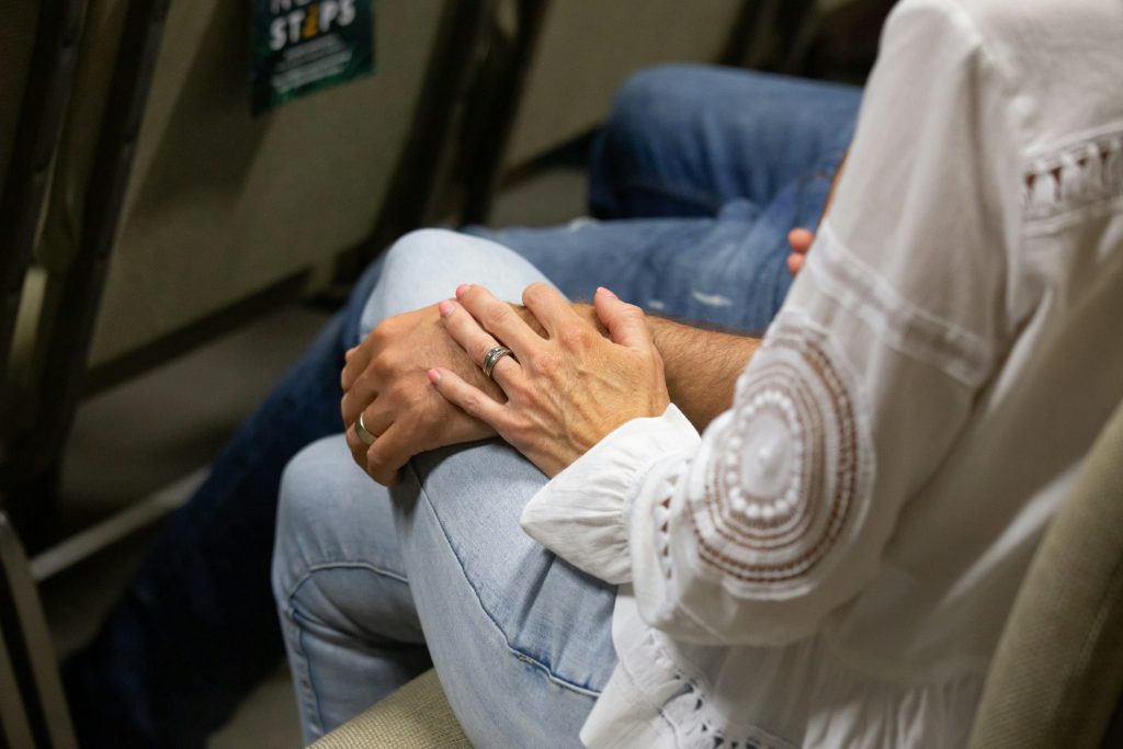 a person sitting on a bench with their hands folded